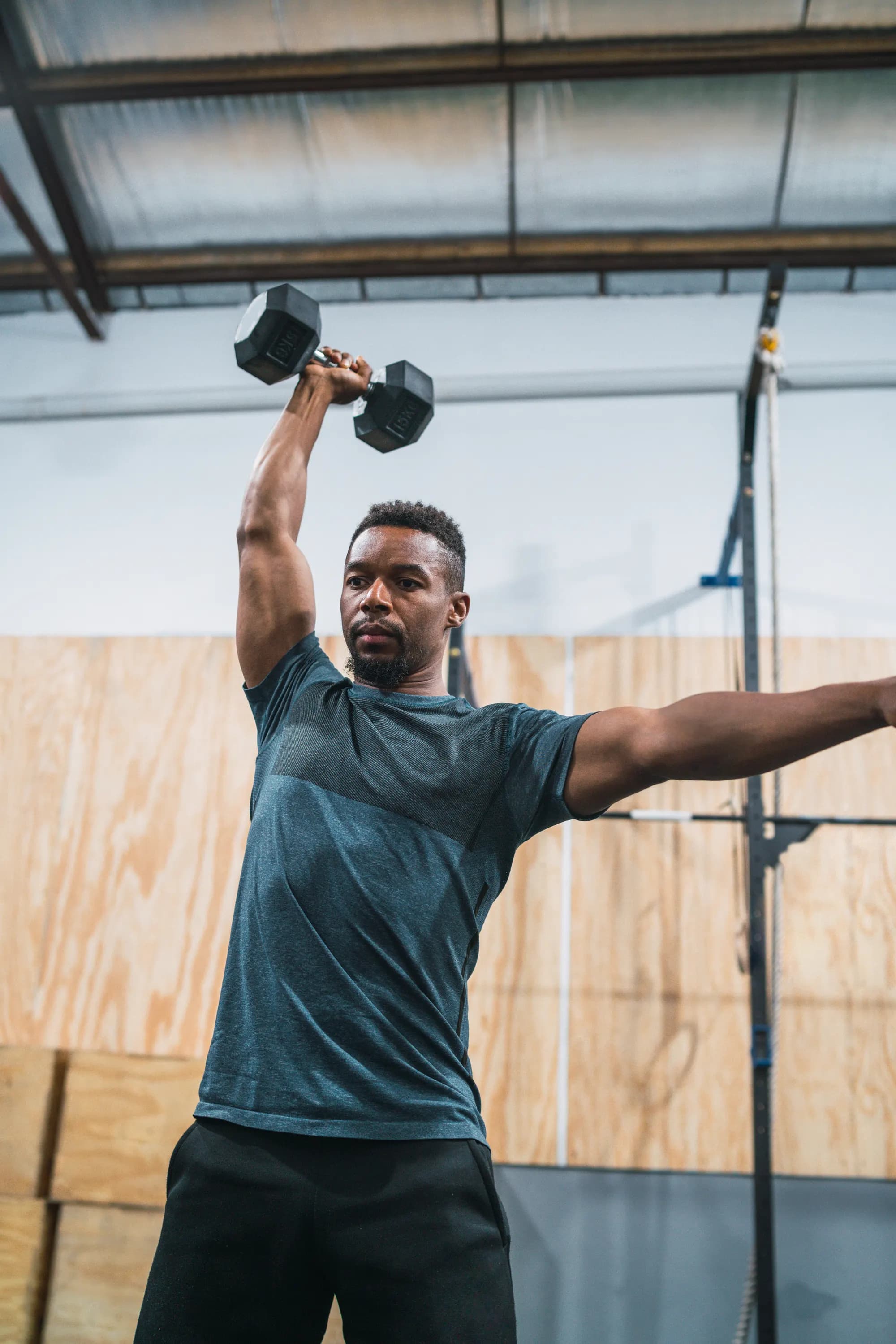 A man pressing a dumbbell overhead during a gym session